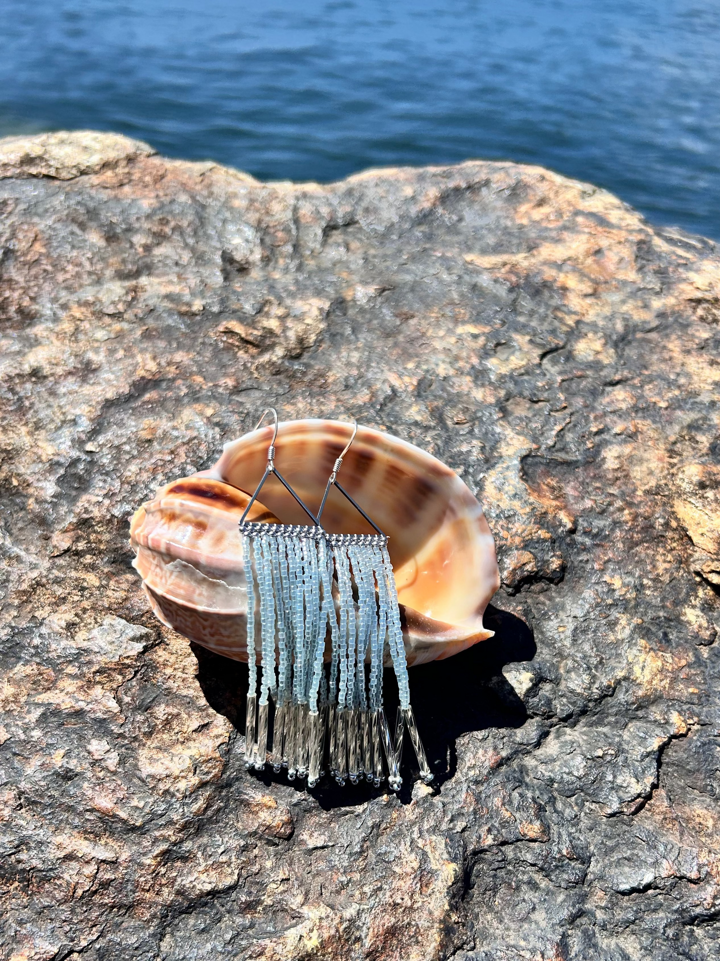 Shell with a decorative hairpiece on a rocky surface near water